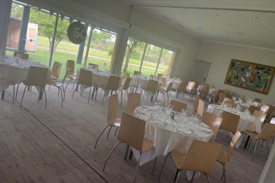 Salle de bain moderne avec douche arrondie, lavabo avec miroir éclairé et carrelage sombre.