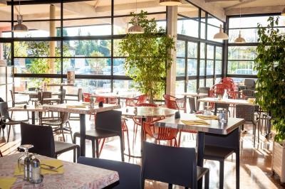 Façade d'un restaurant moderne avec terrasse, grandes baies vitrées et enseigne ’Restaurant Le Bon Plan’.