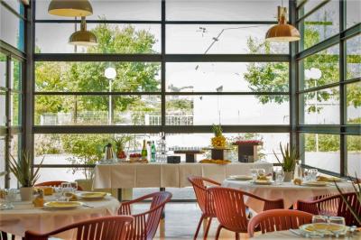 Façade d'un restaurant moderne avec terrasse, grandes baies vitrées et enseigne ’Restaurant Le Bon Plan’.