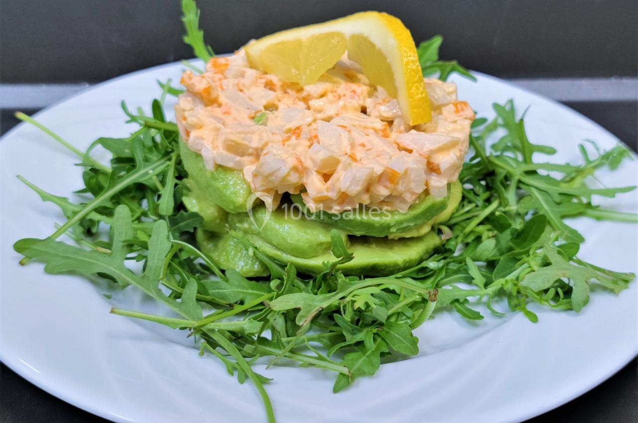 Assiette garnie de roquette, tranches d'avocat, mélange crémeux aux légumes et citron en décoration.