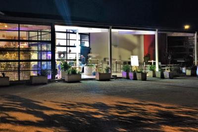 Façade d'un restaurant moderne avec terrasse, grandes baies vitrées et enseigne ’Restaurant Le Bon Plan’.