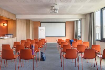 Salle lumineuse avec tables en marbre, chaises modernes, étagères décoratives et un bar en arrière-plan.