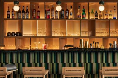 Salle lumineuse avec tables en marbre, chaises modernes, étagères décoratives et un bar en arrière-plan.