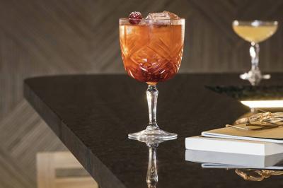 Salle lumineuse avec tables en marbre, chaises modernes, étagères décoratives et un bar en arrière-plan.