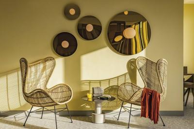 Salle lumineuse avec tables en marbre, chaises modernes, étagères décoratives et un bar en arrière-plan.