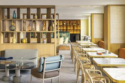 Salle lumineuse avec tables en marbre, chaises modernes, étagères décoratives et un bar en arrière-plan.