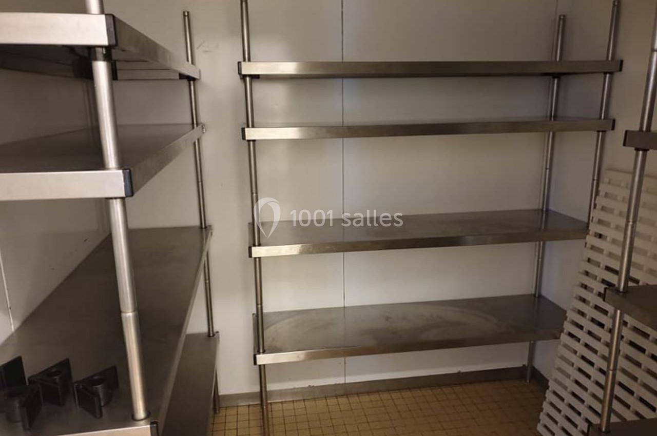 Étagères métalliques vides fixées au mur dans une pièce au sol carrelé beige.