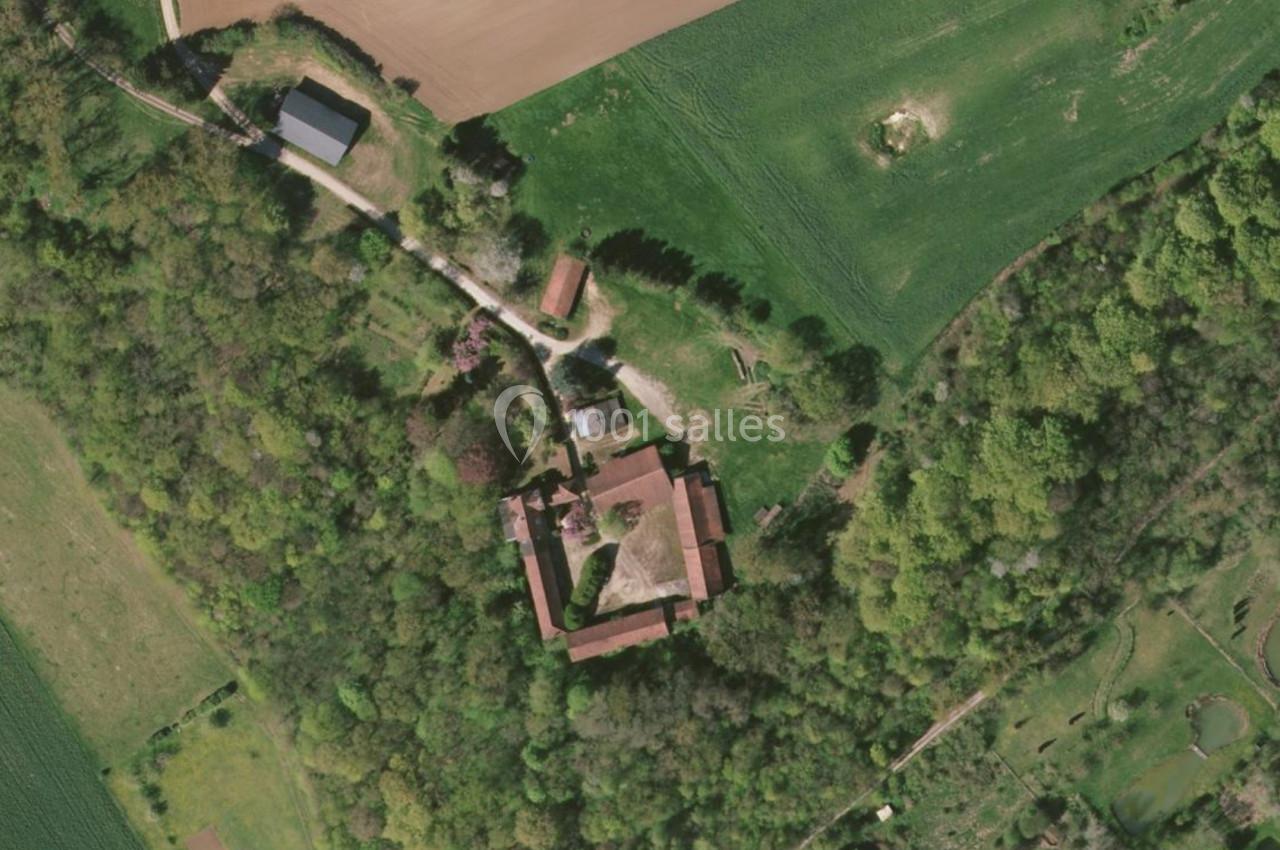 Vue aérienne d'un domaine entouré de forêts et de champs, avec plusieurs bâtiments et chemins visibles.