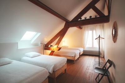 Salle de bain lumineuse avec baignoire moderne, échelle en bois, miroir incliné et double vasque sur meuble blanc.