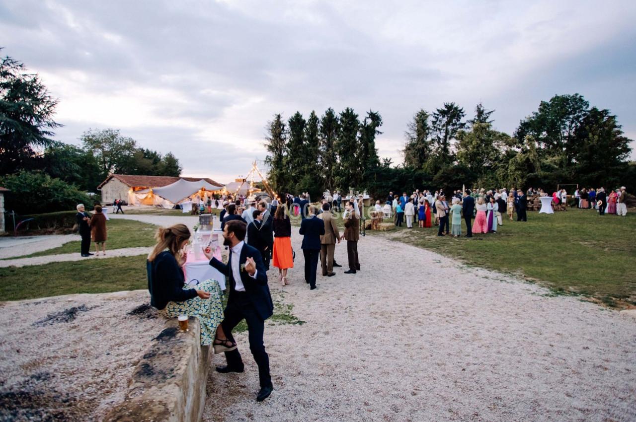 Groupe de personnes rassemblées en extérieur lors d'un événement festif, avec des tentes et des arbres en arrière-plan.