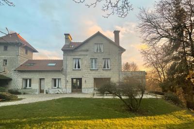 Salle de bain lumineuse avec baignoire moderne, échelle en bois, miroir incliné et double vasque sur meuble blanc.