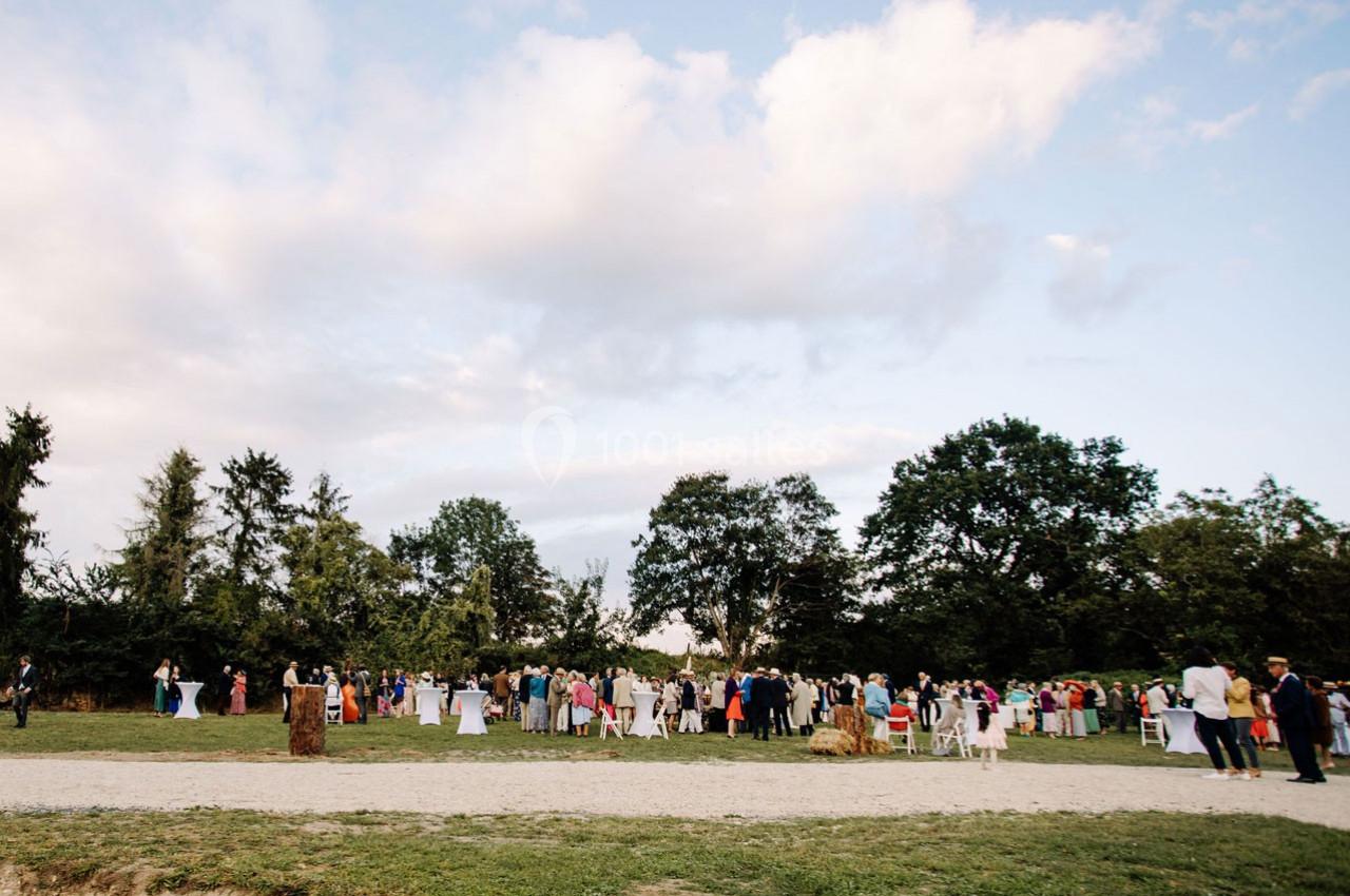 Groupe de personnes rassemblées en plein air dans un parc, sous un ciel partiellement nuageux.