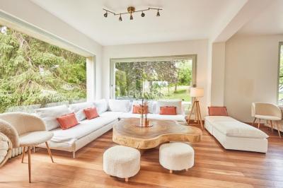 Salle de bain lumineuse avec baignoire moderne, échelle en bois, miroir incliné et double vasque sur meuble blanc.