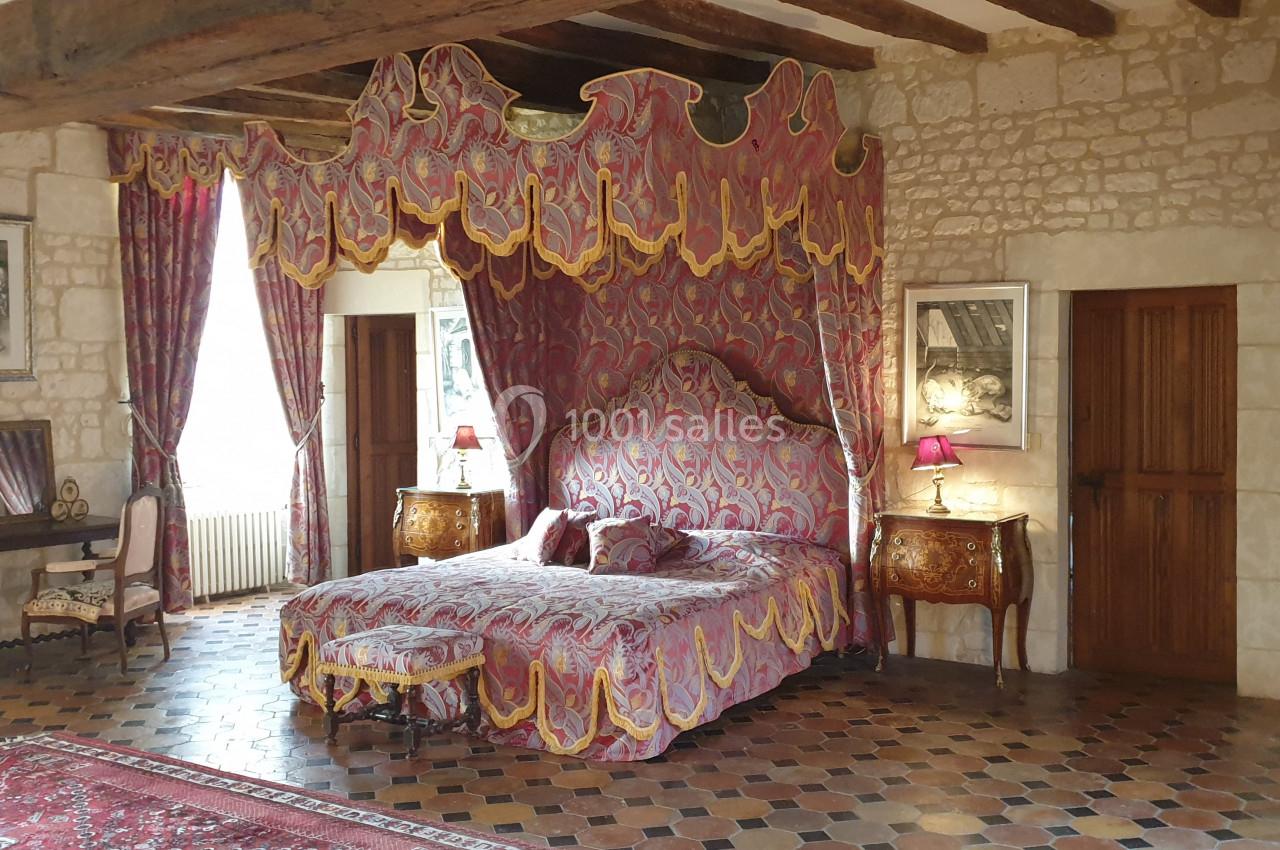 Location salle Assay (Indre-et-Loire) - Chateau de Basché #8 Chambre avec lit à baldaquin, rideaux décoratifs, meubles anciens et murs en pierre apparente.