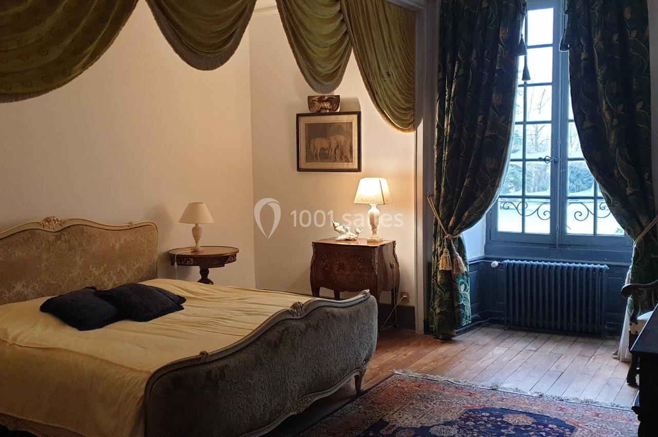 Location salle Assay (Indre-et-Loire) - Chateau de Basché #11 Chambre avec lit ancien, rideaux dorés, mobilier d'époque et fenêtre donnant sur un extérieur arboré.