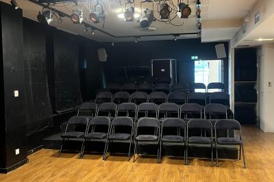 Tables dressées avec nappes, bouteilles, verres et un bouquet de fleurs dans une salle lumineuse avec de grandes fenêtres.
