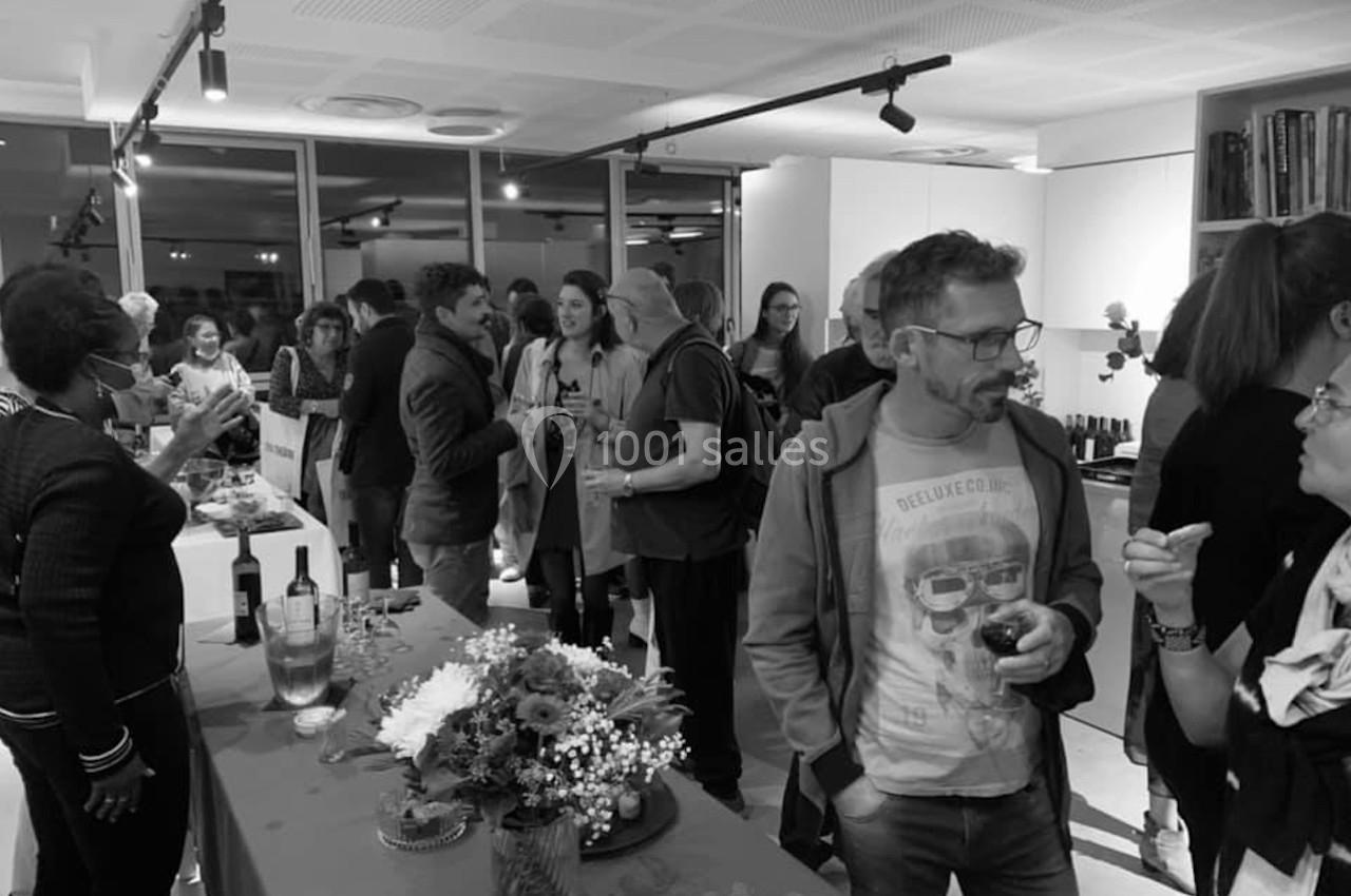 Des personnes discutent et partagent un verre lors d'un événement convivial dans une salle lumineuse.