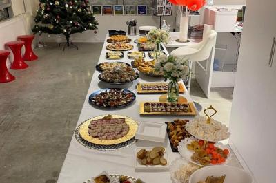 Tables dressées avec nappes, bouteilles, verres et un bouquet de fleurs dans une salle lumineuse avec de grandes fenêtres.