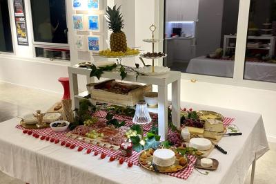 Tables dressées avec nappes, bouteilles, verres et un bouquet de fleurs dans une salle lumineuse avec de grandes fenêtres.