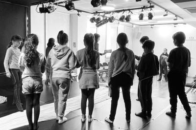 Tables dressées avec nappes, bouteilles, verres et un bouquet de fleurs dans une salle lumineuse avec de grandes fenêtres.