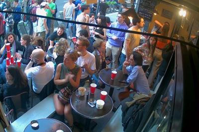 Verres de cocktails variés, dont des shots avec citrons verts et des spritz orange, posés sur des tables en bois.