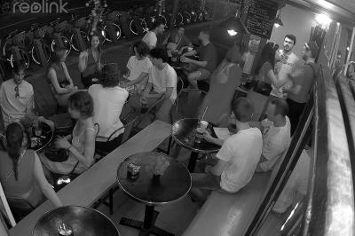 Verres de cocktails variés, dont des shots avec citrons verts et des spritz orange, posés sur des tables en bois.