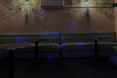 Verres de cocktails variés, dont des shots avec citrons verts et des spritz orange, posés sur des tables en bois.