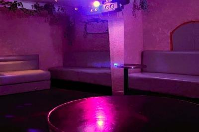 Verres de cocktails variés, dont des shots avec citrons verts et des spritz orange, posés sur des tables en bois.