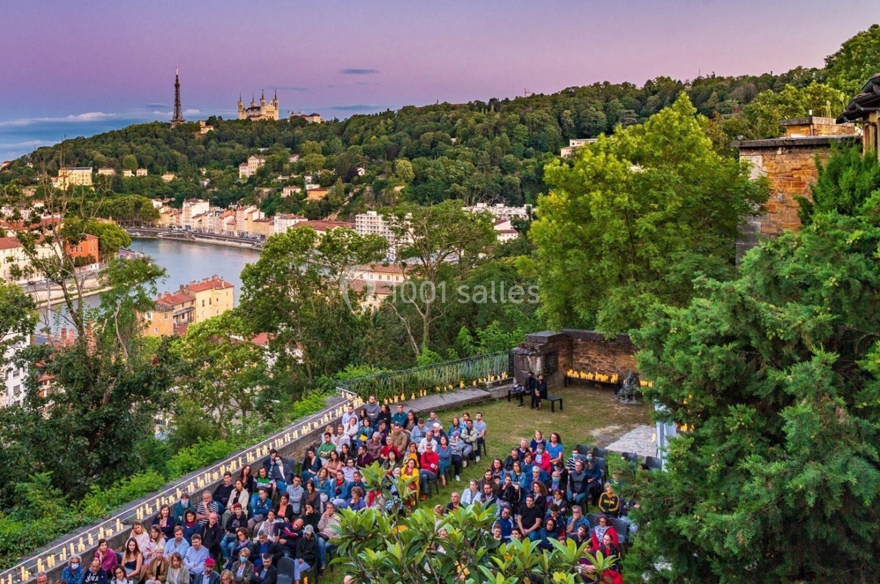Vue d'un événement en plein air avec des participants, surplombant une ville, une rivière et des collines verdoyantes au…