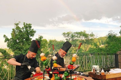 Tables rondes dressées avec nappes noires, serviettes pliées et verres dans une salle lumineuse avec grandes fenêtres.
