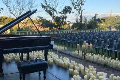 Tables rondes dressées avec nappes noires, serviettes pliées et verres dans une salle lumineuse avec grandes fenêtres.
