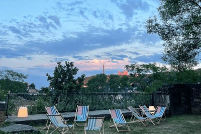 Tables rondes dressées avec nappes noires, serviettes pliées et verres dans une salle lumineuse avec grandes fenêtres.