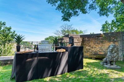 Tables rondes dressées avec nappes noires, serviettes pliées et verres dans une salle lumineuse avec grandes fenêtres.