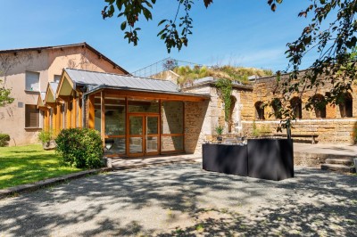 Tables rondes dressées avec nappes noires, serviettes pliées et verres dans une salle lumineuse avec grandes fenêtres.