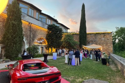 Tables rondes dressées avec nappes noires, serviettes pliées et verres dans une salle lumineuse avec grandes fenêtres.