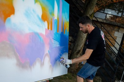 Tables rondes dressées avec nappes noires, serviettes pliées et verres dans une salle lumineuse avec grandes fenêtres.