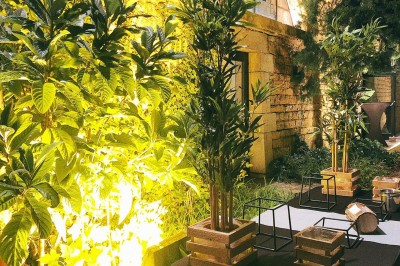 Tables rondes dressées avec nappes noires, serviettes pliées et verres dans une salle lumineuse avec grandes fenêtres.