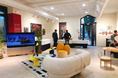 Tables rondes dressées avec nappes noires, serviettes pliées et verres dans une salle lumineuse avec grandes fenêtres.