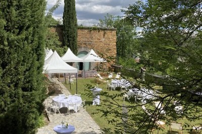 Tables rondes dressées avec nappes noires, serviettes pliées et verres dans une salle lumineuse avec grandes fenêtres.