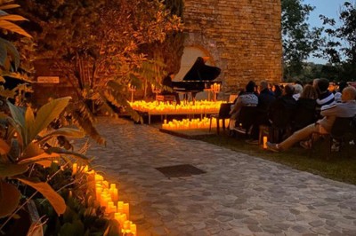 Tables rondes dressées avec nappes noires, serviettes pliées et verres dans une salle lumineuse avec grandes fenêtres.