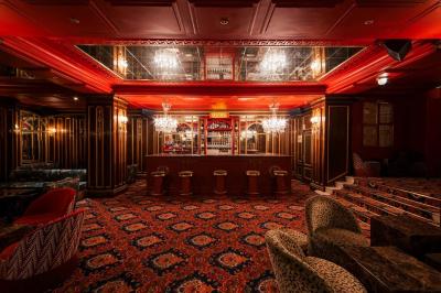 Escalier et couloir décoré de rouge avec fresque murale sculptée, éclairage chaleureux et moquette au sol.