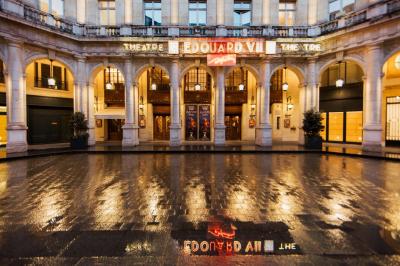 Escalier et couloir décoré de rouge avec fresque murale sculptée, éclairage chaleureux et moquette au sol.