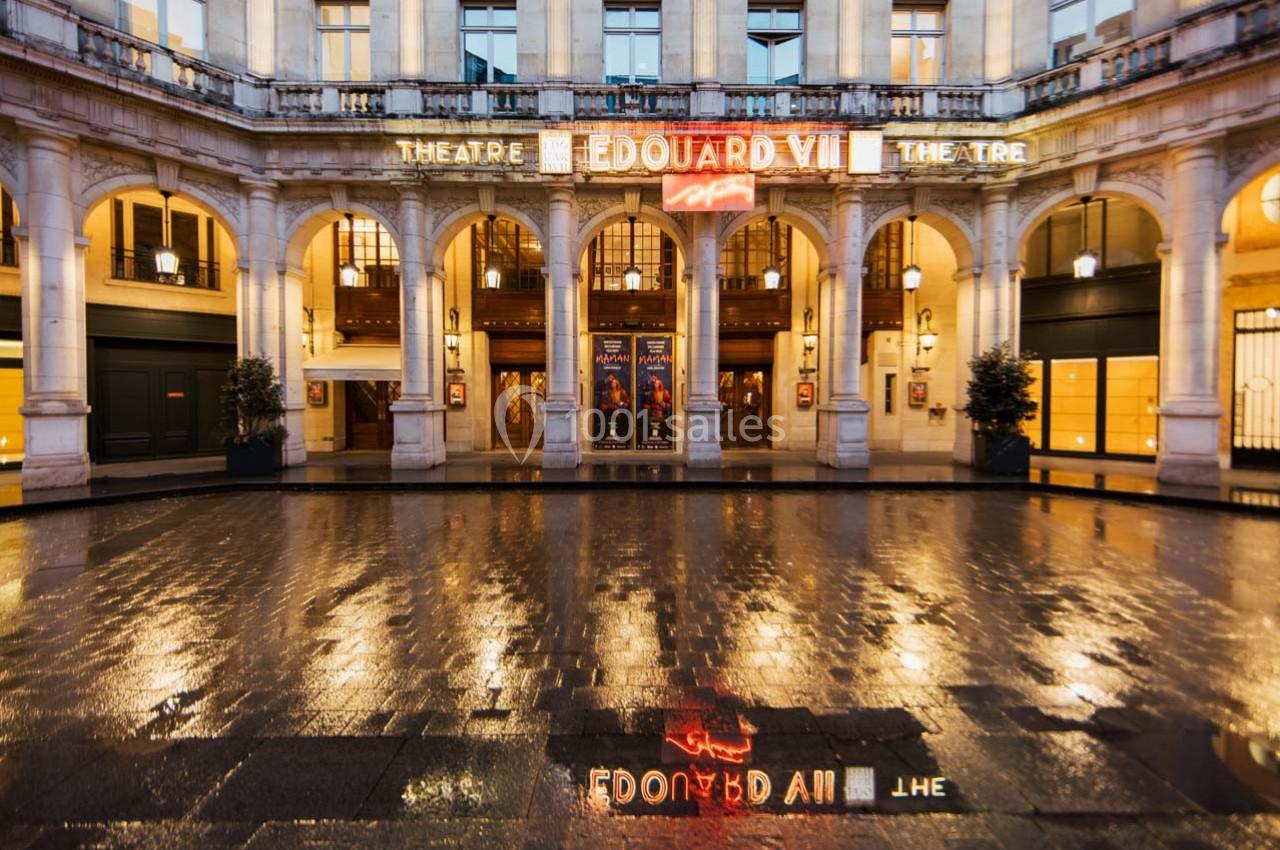Façade illuminée du théâtre Édouard VII avec affiches et reflets sur le sol mouillé.