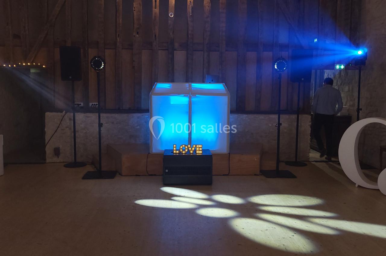 Scène de mariage avec une piste de danse éclairée, une décoration ’LOVE’ lumineuse et des projecteurs bleus.
