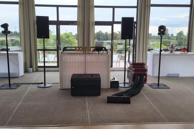 Homme souriant portant un casque audio et un costume sombre, éclairé par une lumière douce sur fond noir.