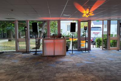 Homme souriant portant un casque audio et un costume sombre, éclairé par une lumière douce sur fond noir.