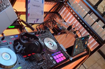 Homme souriant portant un casque audio et un costume sombre, éclairé par une lumière douce sur fond noir.