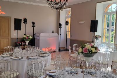 Homme souriant portant un casque audio et un costume sombre, éclairé par une lumière douce sur fond noir.