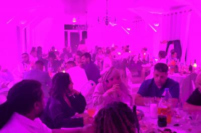 Homme souriant portant un casque audio et un costume sombre, éclairé par une lumière douce sur fond noir.