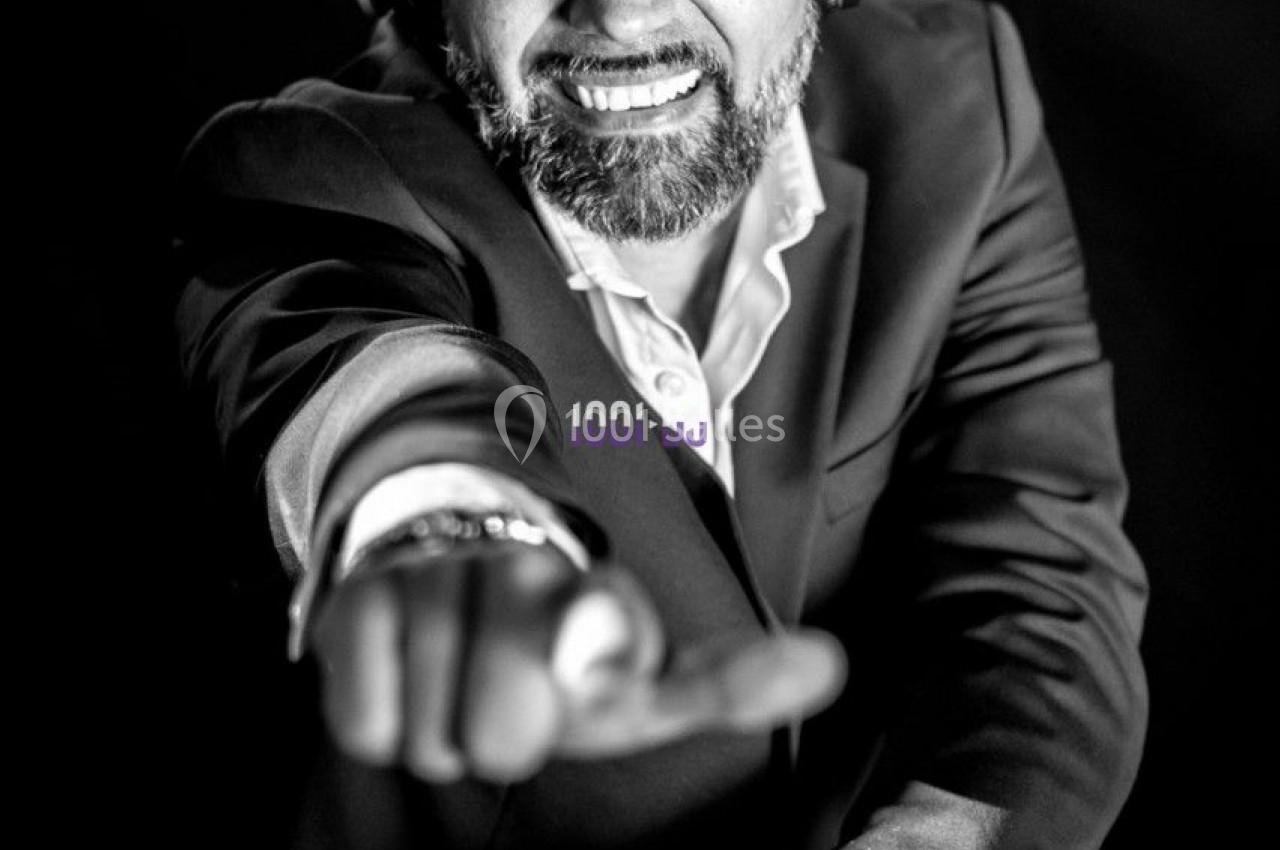 Un DJ souriant portant un casque audio, pointant vers l'objectif dans une ambiance en noir et blanc.